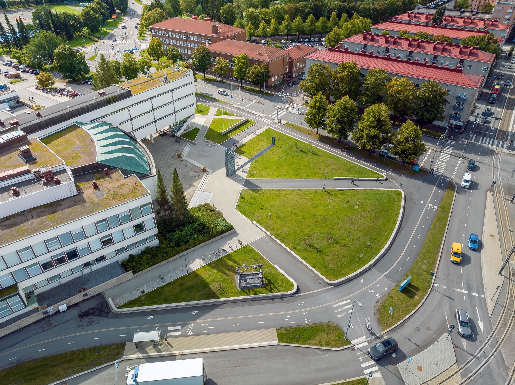 Kuvassa on Sammon aukio ja Sampola. Aukiolla on isoja nurmialueita. Aukion vieressä on kevyen liikenteen väylä.