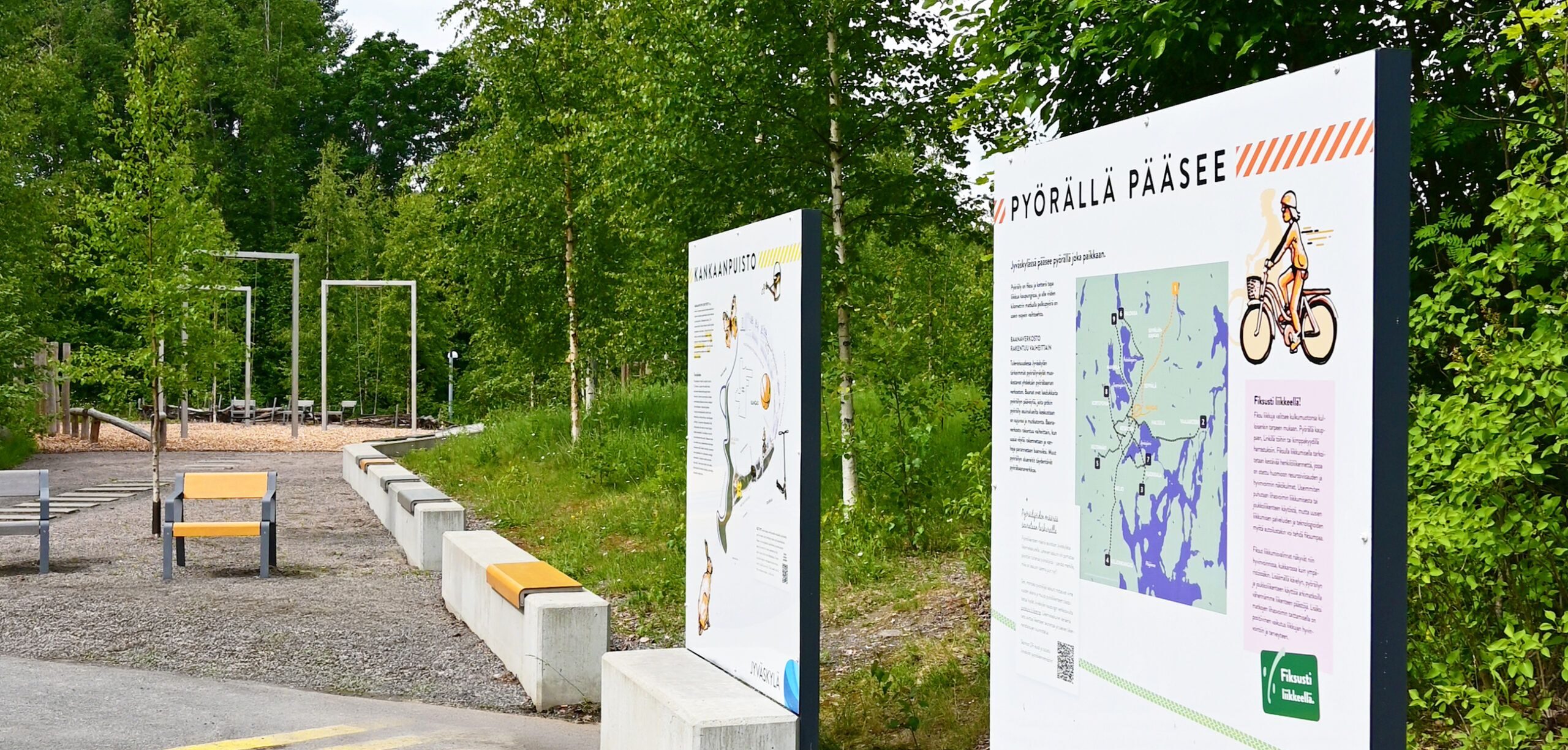 Kuvassa on kaksi infokylttiä Kankaanpuistossa. Taustalla on leikkipaikka.